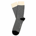 A pair of crew socks with thin black and white horizontal stripes, featuring solid black toes and heels, and a contrasting cream-colored ribbed cuff.